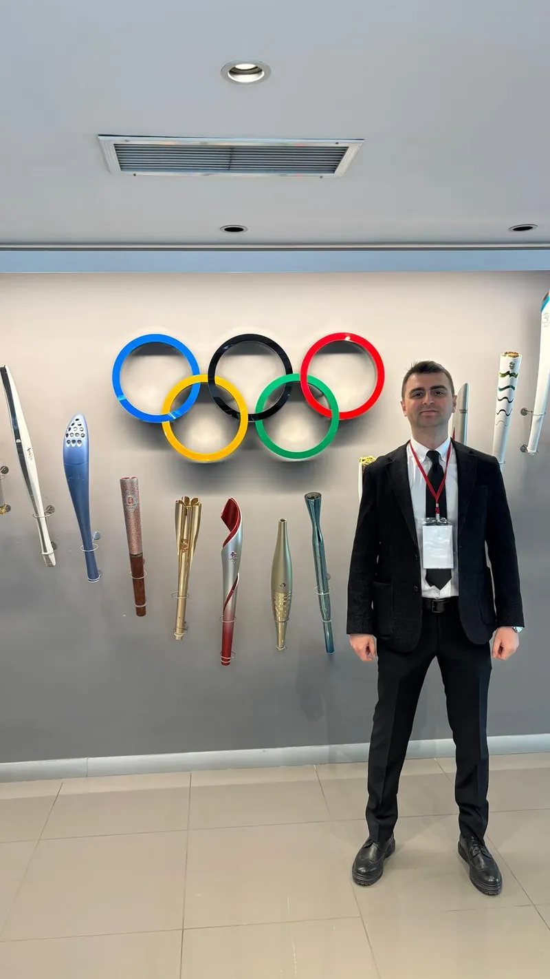 Dr. Mehmet Kaymakoğlu olimpiyat halkaları önünde poz verirken